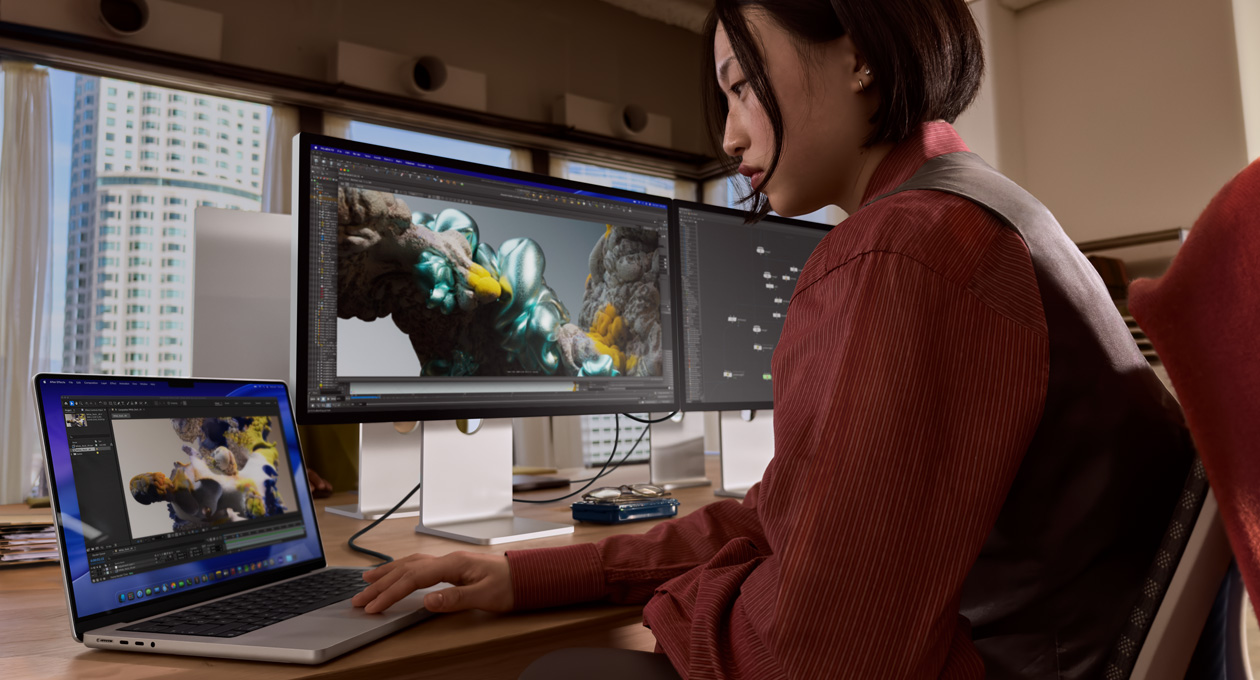 Osoba u uredskom okruženju radi na MacBook prijenosniku povezanom sa zaslonom Studio Display XDR putem priključka Thunderbolt 5