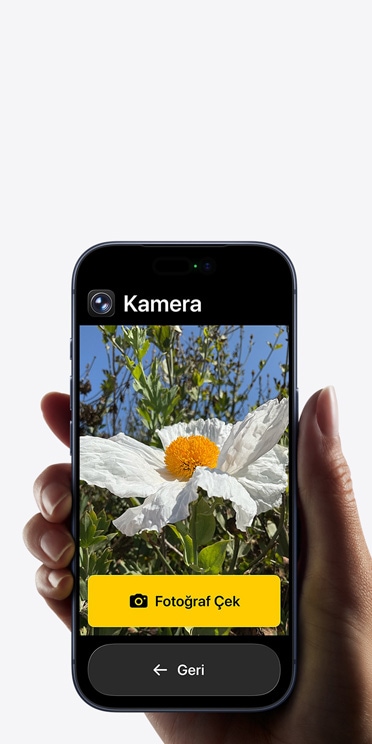 Kadrajında beyaz çiçek bulunan Kamera uygulamasının basitleştirilmiş arayüzünü, “Fotoğraf Çek” düğmesini ve altındaki “Geri” düğmesini gösteren iPhone 17 Pro ekranı