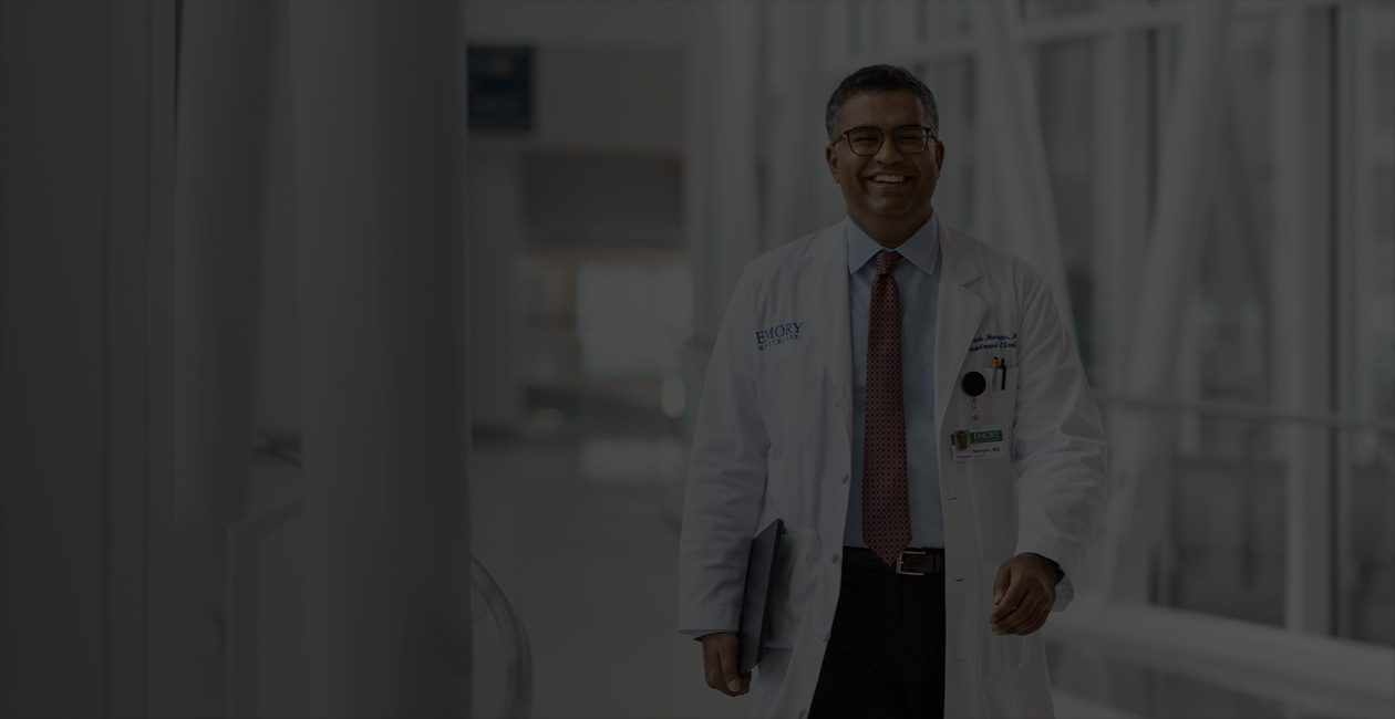 Un médico camina con un MacBook bajo el brazo derecho.