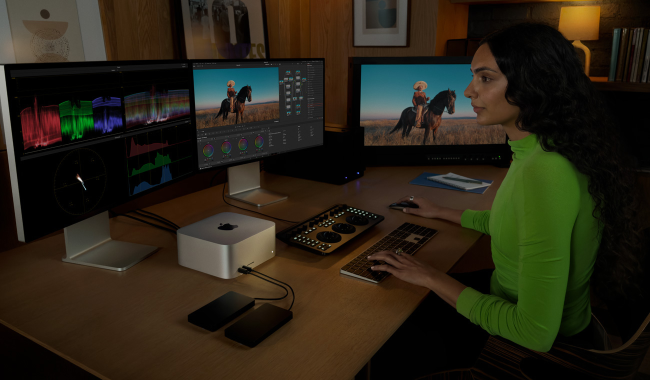 Une personne retouche des fichiers sur un Mac Studio connecté à trois écrans